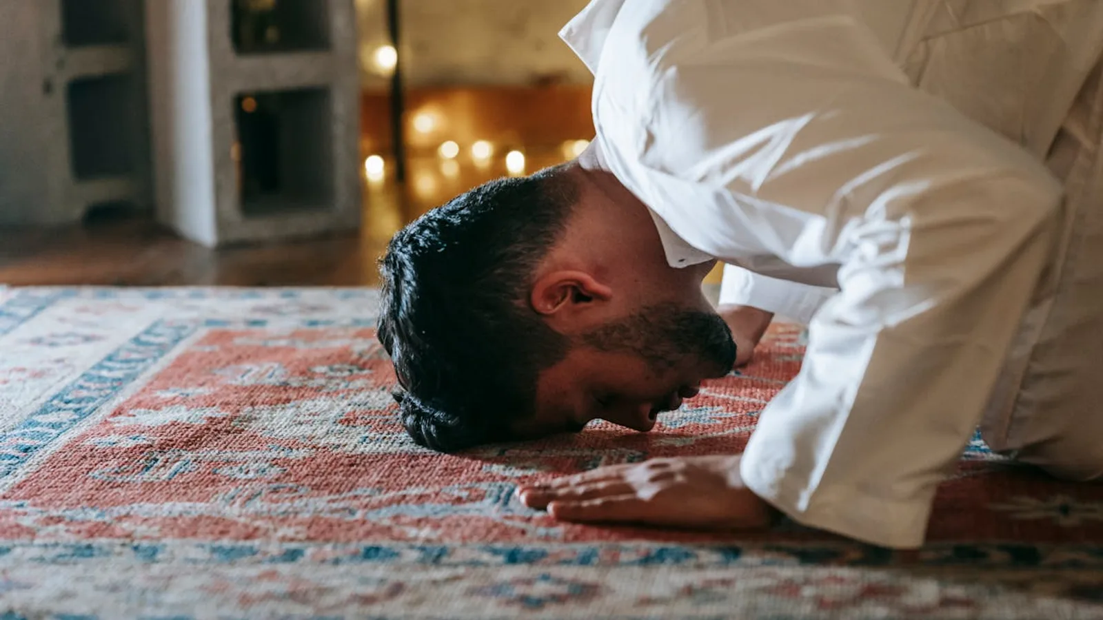 Un homme en prosternation (sujûd) sur un tapis de prière, le front et les mains posés au sol