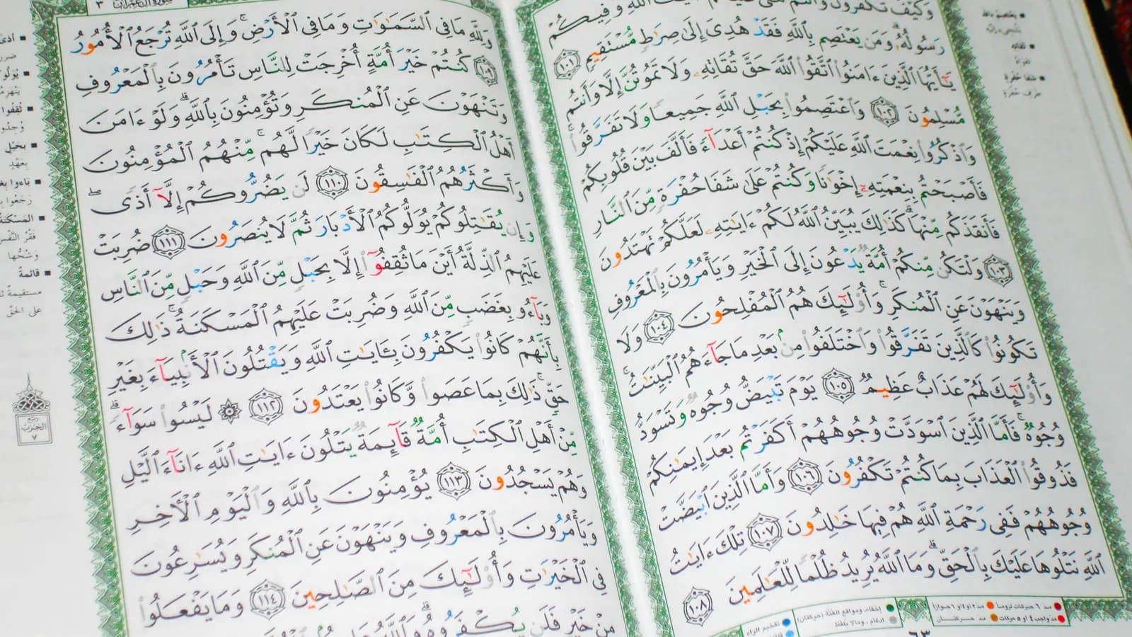 Un Coran ouvert, en gros plan, sur ses pages calligraphiées encadrées de vert