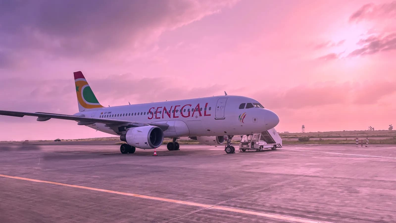 Un avion aux couleurs d’Air Sénégal sur le tarmac de l’aéroport international Blaise-Diagne, près de Dakar, sous un ciel rose de coucher de soleil