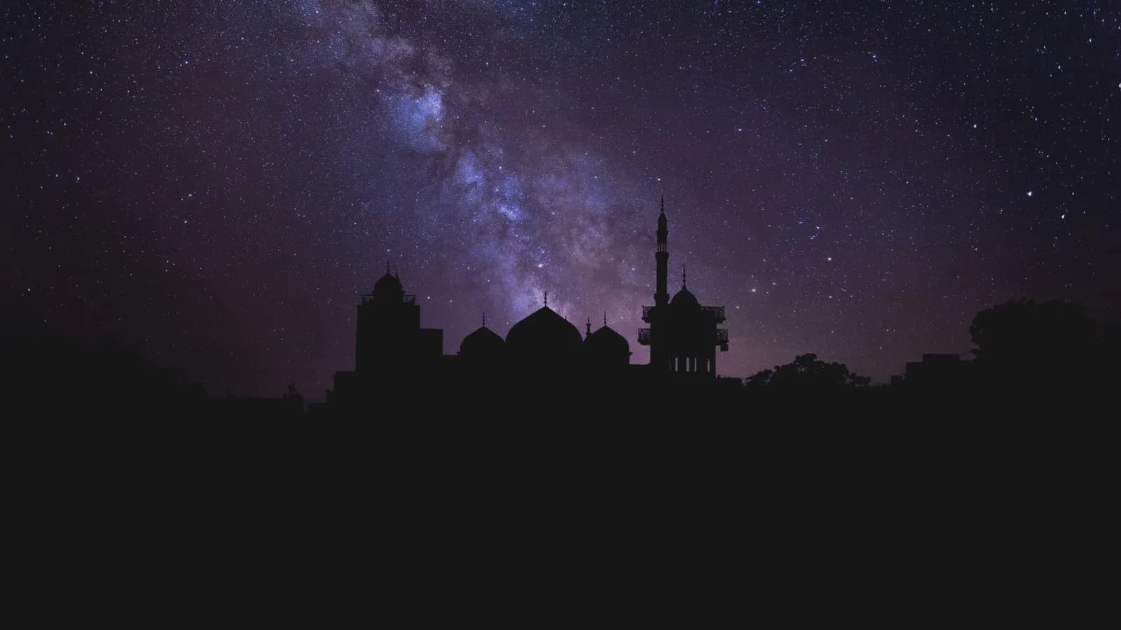 La Voie lactée dans un ciel étoilé, au-dessus de la silhouette d’une mosquée et de son minaret